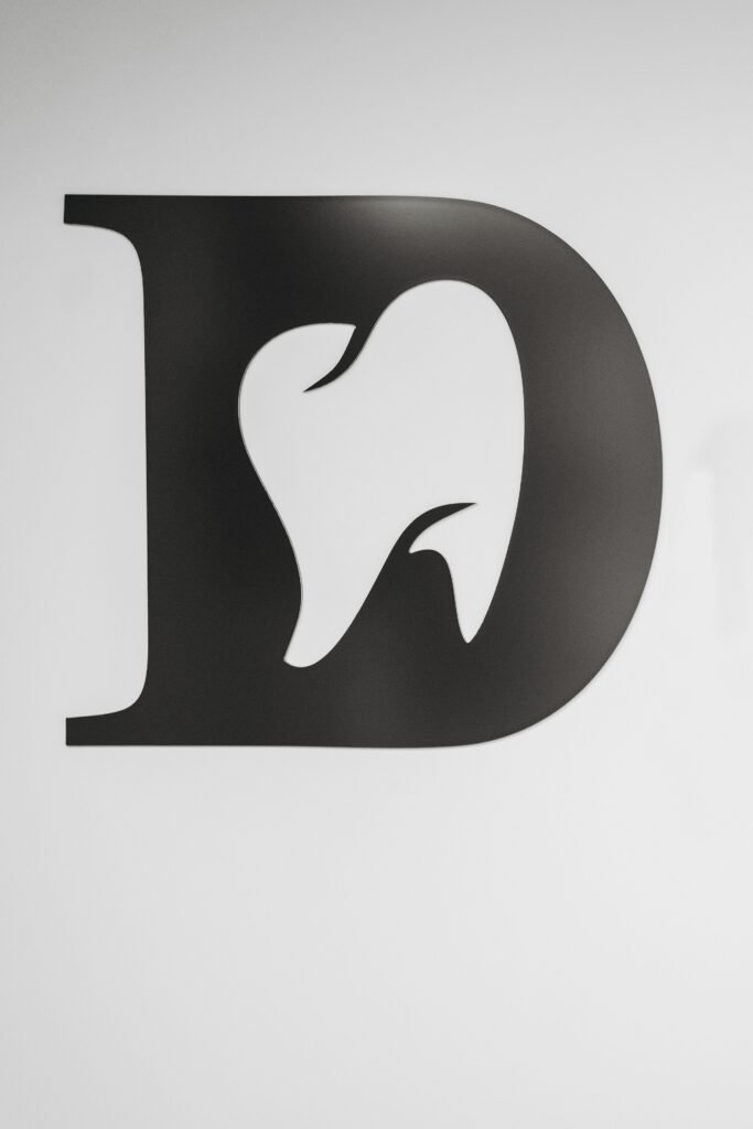 Simple black and white tooth design within letter D, ideal for dental branding.